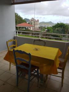 a yellow table and chairs on a balcony at LES FEUILLAGES in Le Marin