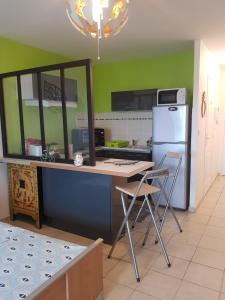 a kitchen with a table and two chairs and a refrigerator at LES FEUILLAGES in Le Marin