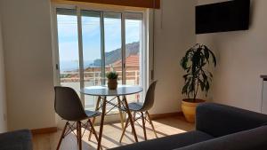 un soggiorno con tavolo, sedie e finestra di Amazing view over the sea and village a Nazaré