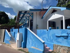 a house with blue walls and stairs in front at Villa Manoir in Anse Lazio