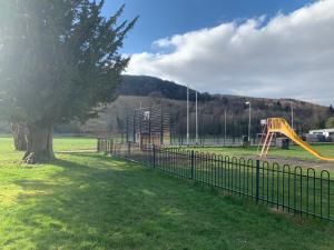 un parque infantil con un árbol y un tobogán en The Clachan Flat en Rosneath