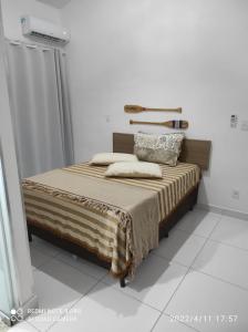 a bed in a white room with a bed sidx sidx sidx at Confortável Duplex a 100 Metros da Praia in Porto Seguro