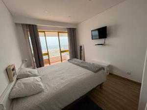 a bedroom with a bed with a television on the wall at Pé no mar - Monte Gordo in Monte Gordo