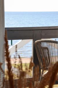 a chair sitting on a balcony overlooking the ocean at Prie Mariu in Nida