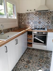 cocina con armarios blancos y suelo de baldosa en La CABANE AUX ECREVISSES - LES PIEDS DANS L'EAU, en Châteauneuf-les-Bains