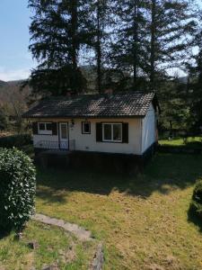 a small white house in a yard with trees at La CABANE AUX ECREVISSES - LES PIEDS DANS L'EAU in Châteauneuf-les-Bains +7 photos