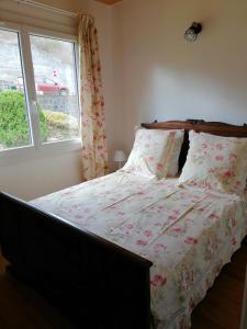 a bedroom with a bed with a floral comforter and a window at La CABANE AUX ECREVISSES - LES PIEDS DANS L'EAU in Châteauneuf-les-Bains