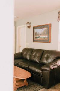 un divano in pelle marrone in un soggiorno con tavolo di The Long Barn Lodge a Long Barn