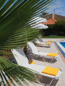 a group of white lounge chairs and a palm tree at Villa Lemonia in Malia