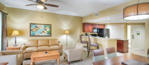 a living room with a couch and a table and a kitchen at Club Wyndham Cypress Palms in Kissimmee