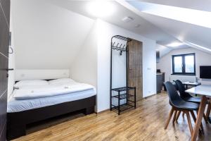 a bedroom with a bed and a desk and chairs at PLESSBERG Apartments Plešivec in Abertamy