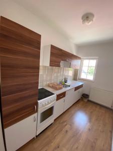 La cuisine est équipée de placards en bois et d'un four avec plaques de cuisson. dans l'établissement Apartmani Jovana, à Jagodina