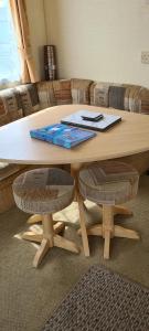 una mesa de madera con 2 taburetes y una mesa con ordenador portátil en Willerby Calypso, en Looe