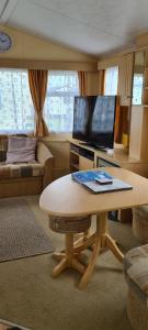 a living room with a table and a flat screen tv at Willerby Calypso in Looe