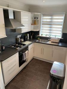 uma cozinha com armários brancos e um forno com placa de fogão em One bed cozy flat em Dartford