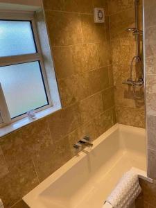 One bed cozy flat في دارتفورد: حمام مع حوض استحمام ونافذة