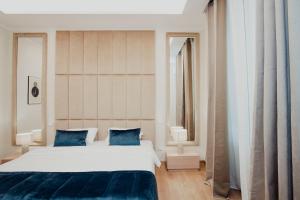 a bedroom with a large white bed with blue pillows at Cesare ai Cavalieri Suites in Rome