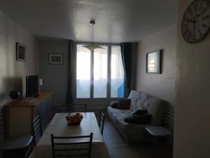 ein Wohnzimmer mit einem Sofa, einem Tisch und einer Uhr in der Unterkunft Appartement restauré à 50 m de la plage in Saint-Hilaire-de-Riez