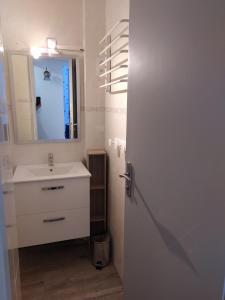 a white bathroom with a sink and a mirror at Appartement restauré à 50 m de la plage in Saint-Hilaire-de-Riez +16 photos
