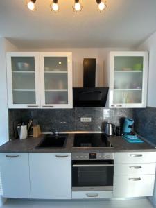 a kitchen with white cabinets and a stove top oven at Villa Sun&Sea in Komarna