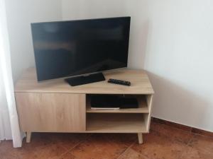 a television on a wooden stand with a remote control at Casa do Mar in Foz do Arelho