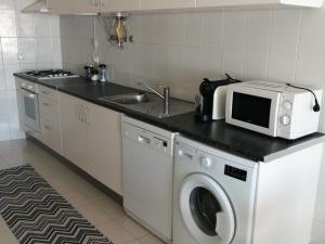 a kitchen with a washing machine and a microwave at Casa do Mar in Foz do Arelho