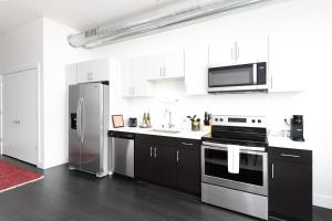 a kitchen with white cabinets and a stainless steel refrigerator at Flexhome Skywalk to Fiserv 1BR Apt U5 - READ INFO in Milwaukee