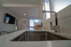 a kitchen with a stainless steel sink and a window at Precioso ático con vistas al mar Parking gratuito in Corralejo