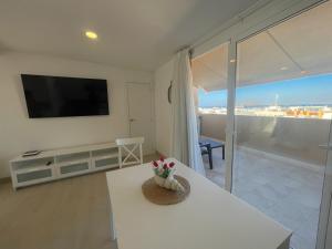 a living room with a white table and a flat screen tv at Precioso ático con vistas al mar Parking gratuito in Corralejo