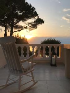 a white rocking chair sitting on a balcony with the sunset at Luxury Mantinela Apartment in Malinska