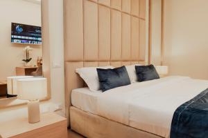 a bedroom with a large white bed with blue pillows at Cesare ai Cavalieri Suites in Rome