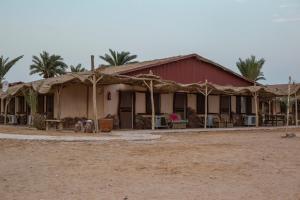 a house with a red building with palm trees at Sayadeen Village - Red Sea Riviera in Nuweiba