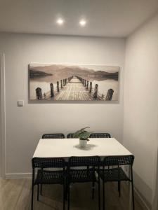 a table with chairs and a painting of a pier at Apartament 80’s in Kołobrzeg +7 photos
