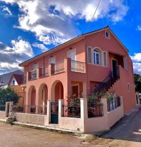 uma casa cor-de-rosa com uma escada ao lado. em Melissani House em Karavomylos