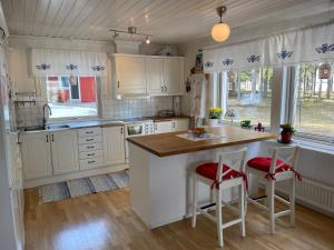 uma cozinha com armários brancos e uma ilha de cozinha com bancos em Beautiful house in the nature with private river access em Luleå