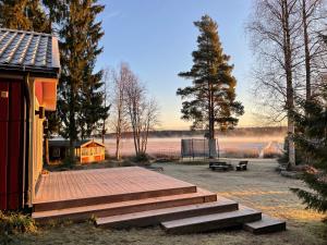 um deque com escadas ao lado de um edifício com um banco em Beautiful house in the nature with private river access em Luleå