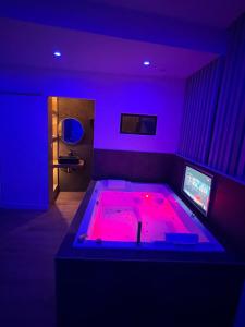 een kamer met een bed met roze verlichting bij Suite & Jacuzzi in Givors