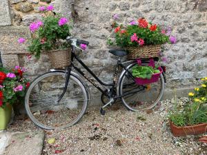 un vélo garé à côté d'un mur de pierre avec des fleurs dans l'établissement la Tourelle en Normandie, à Saint-Pierre-Église