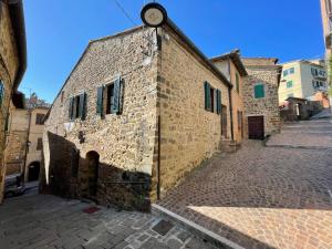 an old stone building with a clock on the side of it at Casa Barcaia Montalcino in Montalcino