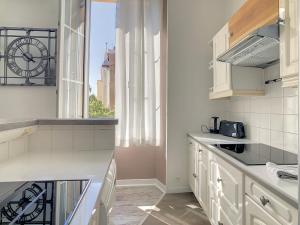 una cocina con armarios blancos y una ventana con reloj en 2 Bedroom luxury flat Cannes Center La Croisette en Cannes