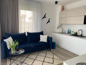 salon z niebieską kanapą i kuchnią w obiekcie Apartament BLUE Rewal w Rewalu
