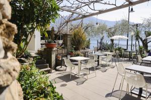 a patio with tables and chairs and the water at La Foresta Monteisola in Monte Isola
