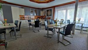 a dining room with tables and chairs and a kitchen at Ferienparadies Gutounik in Pörtschach am Wörthersee