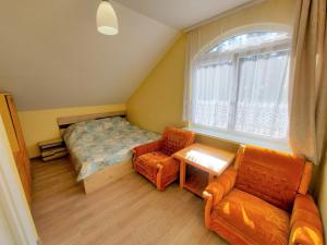 a bedroom with a bed and two chairs and a window at Neringa Guest House in Palanga