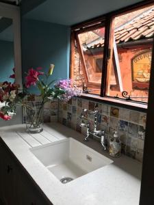 a kitchen sink with a vase of flowers and a window at Dunster Luxe Nook in Dunster