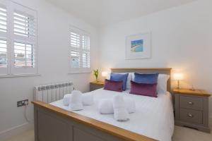 een slaapkamer met een groot wit bed met paarse kussens bij Little Gem in St Ives