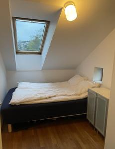 a bed in a small room with a window at The Urban Penthouse in Oslo