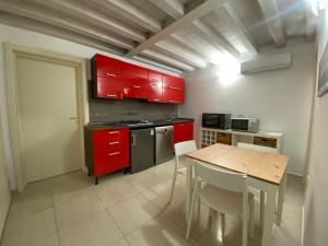 a kitchen with red cabinets and a wooden table at Ca' Contadin in Chioggia