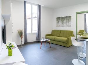 a living room with a green couch and a table at Colours Apartments & Rooms in Sanremo