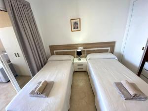 two beds in a hotel room with towels on them at Apartamento Torre Levante, primera línea de playa in Benidorm